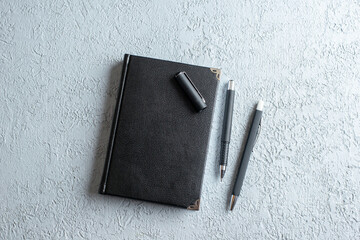 Wall Mural - top view of new closed notebook and pens on gray sand background with free space