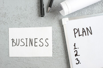 Wall Mural - top view of plan and numbers on white desk blank pens business writing on sheet on gray sand backgro