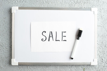 Wall Mural - top view of sale writing on sheet and marker on white desk on gray sand background