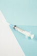 Vertical view of disposable syringe on blue white background with free space