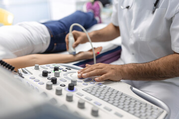 Wall Mural - Cropped view of the male doctor holding special device while making ultrasound therapy for woman. Ultrasound of the veins of the upper xtremities concept