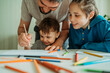 © Westend61 - Smiling father teaching sons to draw using pencil at home