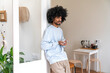 © Westend61 - Man with curly hair holding coffee cup leaning on door at home