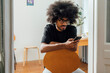 © Westend61 - Man using smart phone sitting on chair at home