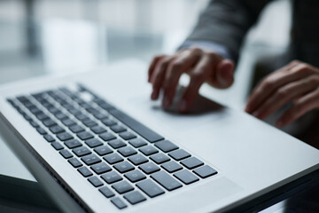 Close-up of male hands using laptop at office