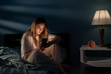 Wall Mural - Young woman awake late at night using smartphone for chatting and sending messages. Internet addiction. Mobile abuse and insomnia concept