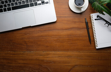 Wall Mural - Top view of laptop computer, coffee cup, notepad and glasses on wooden working desk. Copy space for your text.