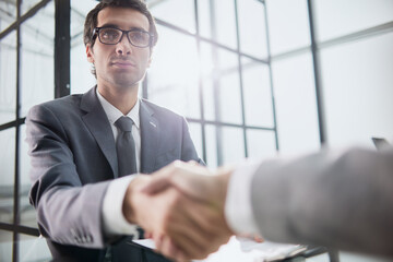 Wall Mural - Man shaking hands with partner over office desk