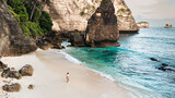 Fototapeta  - Podróżnik idący po pięknej plaży Diamond, na Indonezyjskiej wyspie Nusa Penida, plaża, skały klif oraz ocean.