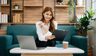 Wall Mural - Business woman using tablet and laptop for doing math finance, tax, report, accounting, statistics, and analytical research concept on sofa in home office.