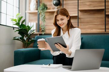 Wall Mural - Business woman using tablet and laptop for doing math finance, tax, report, accounting, statistics, and analytical research concept on sofa in home office.