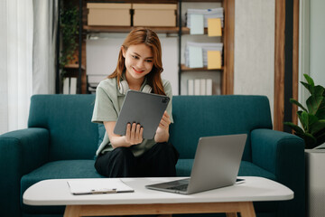 Wall Mural - Business woman using tablet and laptop for doing math finance, tax, report, accounting, statistics, and analytical research concept on sofa in home office.