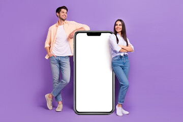 Full size photo of two people showing empty space huge smart phone touchscreen isolated on violet color background