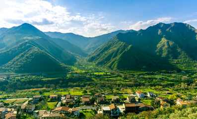 landscape of green summer highland mountain range with green beautiful valley with nice town below a