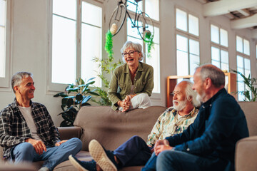 Four senior people talking and laughing while resting in living room.