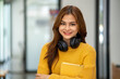 © Wuttichaik - Young Beautiful smiling happy student woman wearing headphone holding a book, Portrait of student girl carry book balancing books on head and hand