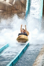 Enthusiastic Young Man Riding Water Log Amusement Park Ride