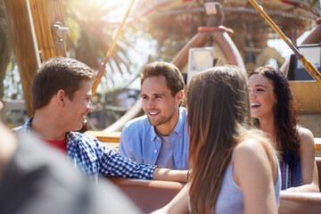 Wall Mural - Smiling friends talking on amusement park ride