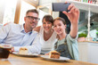 Family with dessert taking selfie at cafe table