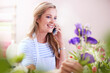 Smiling florist arranging flowers and talking on cell phone