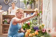 Smiling woman picking out flowers in flower shop