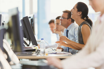 Laughing businesswoman working at computer in office