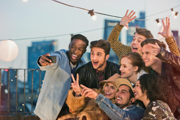 Wall Mural - Enthusiastic young adult friends cheering taking selfie at rooftop party