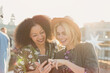 © KOTO - Young women texting with cell phone at rooftop party
