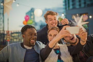 Wall Mural - Young adult friends taking selfie at rooftop party