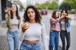© PintoArt - beautiful female friends eating pizza on the street, in the tourist city, focus on curvy latina woman.