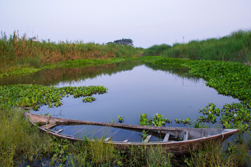 Pond blue water and wooden boat with refleting shore green grass landscape view