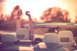 © peterzayda - Relaxing in a convertible during sunset. Happy young woman with her hands up.
