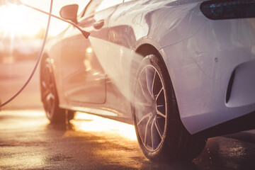 Washing rims at a manual car wash during sunset.