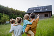 © Halfpoint - Happy family in front of their house with solar panels on the roof.