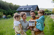 © Halfpoint - Happy family in front of their house with solar panels on the roof.