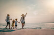© Garun Studios - Happy Asian family consisting of father, mother, Son and daughter having fun playing on the beach.
