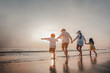© Garun Studios - Happy Asian family consisting of father, mother, Son and daughter having fun playing on the beach.