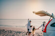© Garun Studios - Asian family vacation holiday, Happy family running on the beach in the sunset.Happy family is running into the sea.Back view of a happy family on a tropical beach and a car on the side.