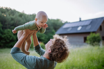 Wall Mural - Boy playing with his little brother in front of their house with solar panels.