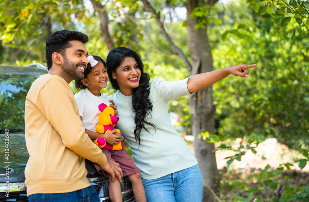 Happy Indian couple showing nature or birds to little girl kid in front ...