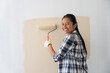 Young asian woman enjoying renovation time at home while holding roller. Repair and remodeling concept
