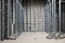 Room Under Construction On A Commercial Construction Project With Metal Studs, PVC Plumbing, And Concrete Walls And Floors. Nobody In The Image With A Horizontal Landscape Orientation.