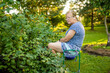 © MNStudio - Beautiful senior woman harvesting black currant berries in a garden. Growing own fruits and vegetables in a homestead.