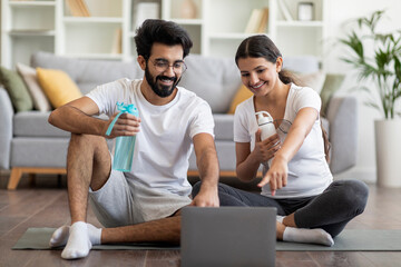 Happy Young Indian Couple Choosing Online Tutorials On Laptop For Home Training