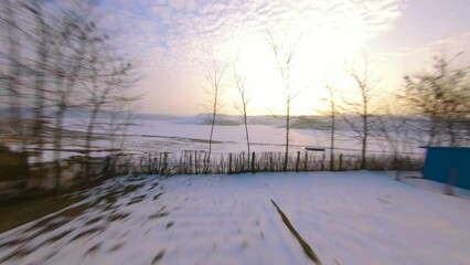 Poster - Drone flying fast over frozen lake with snowy green landscape at sunset in Moldova