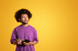 © Prostock-studio - Unhappy pensive black adult curly man in purple t-shirt hold empty wallet, look at free space