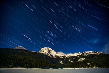 Wall Mural - View of star trails above snow-covered mountains