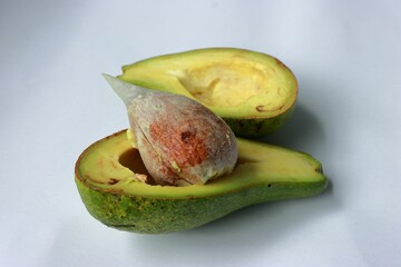 Wall Mural - Ripe avocado split into two halves on a white background