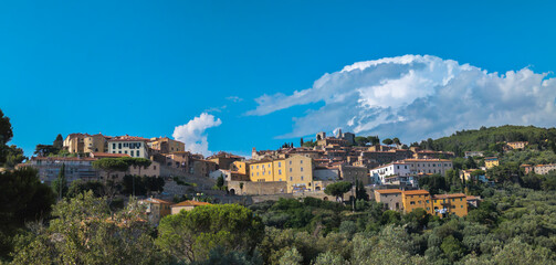 Panoramic view of the Tuscan town of Campiglia Marittima with blue sky and clouds