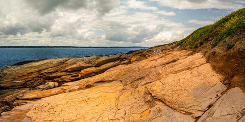 Wall Mural - Slanted hilly rock formation and cloudy seascape at Jamestown beach park in Rhode Island